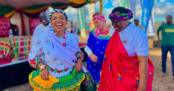 Women smiling together at a colourful community celebration