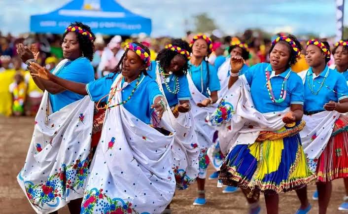 Community dancers wearing bright blue, yellow and patterned clothing